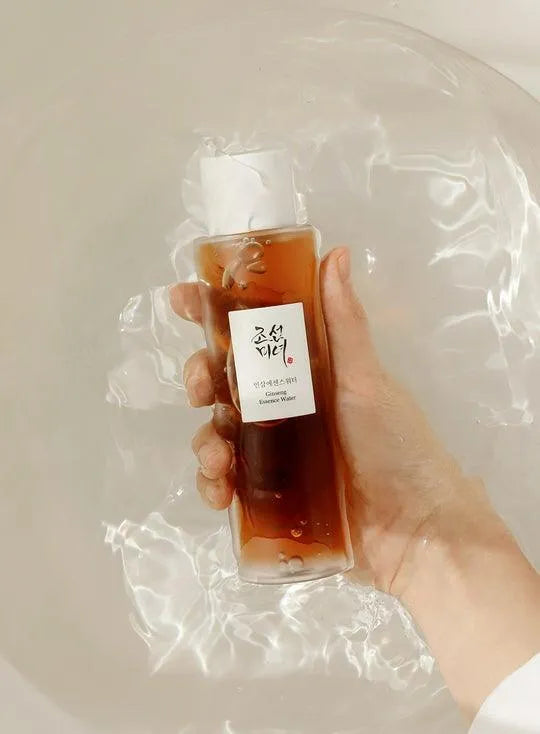 Hand holding Beauty of Joseon Ginseng Essence Water Korean skincare bottle above water