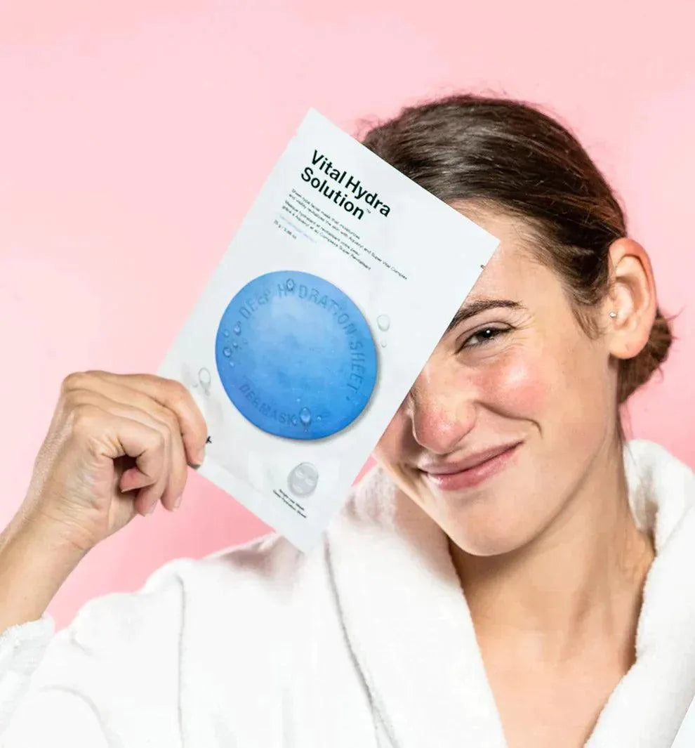 Woman in white robe holding Dr.Jart+ Vital Hydra Solution Korean sheet mask, pink background