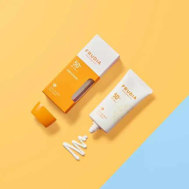 Frudia Tone-Up Base Sun Cream SPF50+ in tube and box on a yellow and blue background, Korean skincare at Me Time Groningen