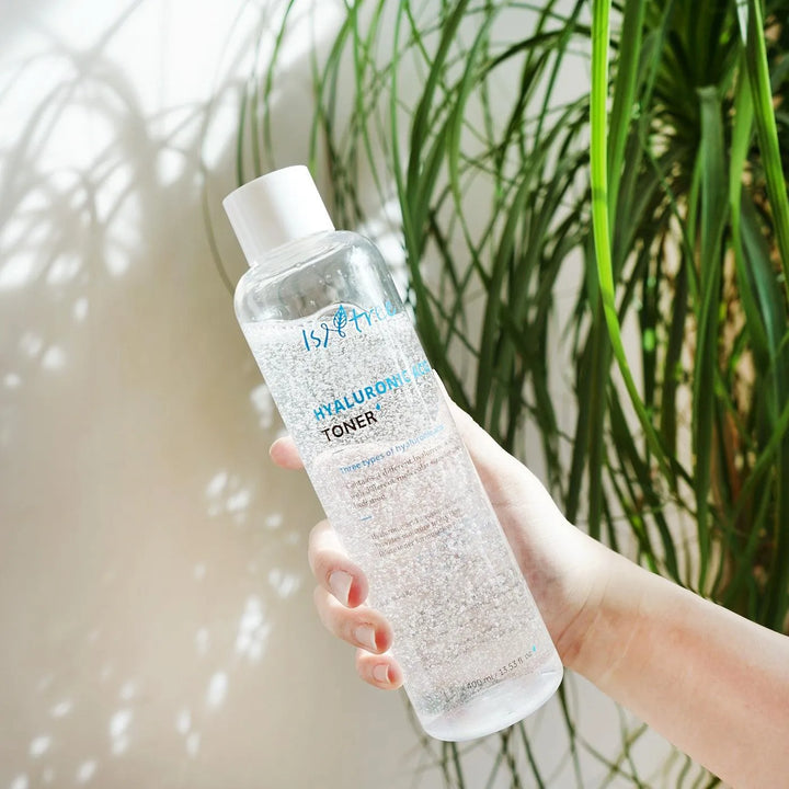 Hand holding Isntree Hyaluronic Acid Toner by a plant, Korean skincare from Me Time Groningen.