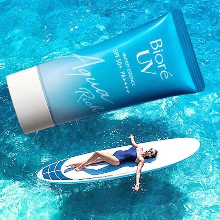 Biore UV Aqua Rich Watery Essence SPF 50+ sunscreen with swimmer on surfboard in blue water