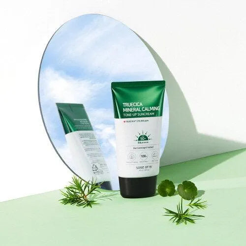 SOME BY MI Truecica Mineral Calming Tone-Up Suncream tube, reflected in a mirror with green leaves, Korean skincare product at Me Time Groningen.